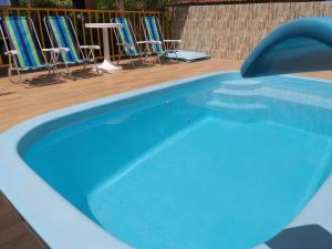 una piscina azul con sillas y mesas en Casa Temporada Maragogi, en Maragogi