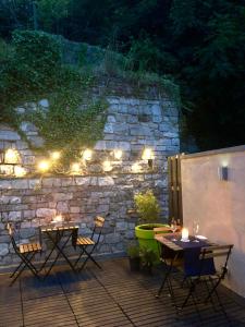 a patio with two tables and lights on a stone wall at Mademoiselle Citadelle in Namur