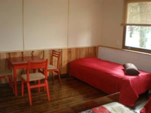 a bedroom with a red bed and a table and chair at Rannakodu in Kabli