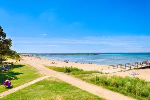 a beach with people in the water and a pier at Mötesplats Borstahusen in Landskrona