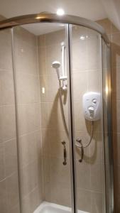 a shower with a glass door and a shower head at Applecroft Bed and Breakfast in St Austell