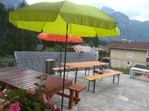 a group of benches and an umbrella on a patio at Ferienhaus Reschreiter in Abtenau