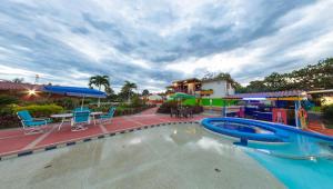 a swimming pool in a resort with chairs and a table at Hotel Campestre Los Tucanes in Armenia