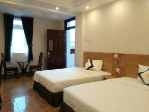 a hotel room with two beds and a table at Thanh Truc Hotel Ca Mau in Cà Mau
