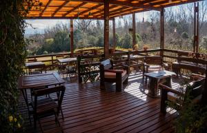 una terraza de madera con mesas y sillas. en Posada La Ensenada en Villa Yacanto