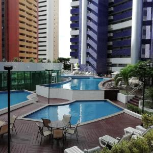 a swimming pool with chairs and tables and buildings at Beach Class Rosalux 707 in Fortaleza