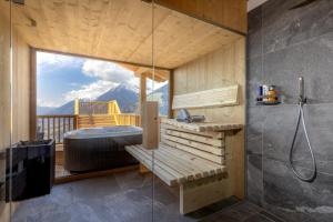 een badkamer met een bad en een douche met uitzicht bij Mountain Village Hasenegg in Schenna