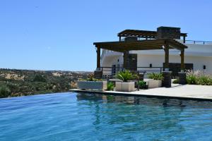 a swimming pool with a pergola next to a house at Vistas - Herdade do Zambujal in Castro Verde