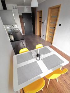 a kitchen with a white table and yellow chairs at Apartament Cyprys 2 in Oświęcim