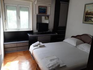 a bedroom with a bed and a desk and a window at Apartmani Ivona in Budva