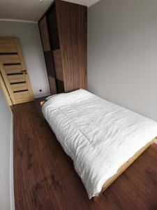 a small bedroom with a white bed and wooden floors at Apartament Cyprys 2 in Oświęcim