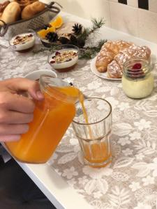 eine Person, die ein Glas Orangensaft auf einen Tisch gießt in der Unterkunft DAD HOME in Cles