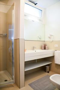 uma casa de banho com um lavatório, um espelho e um chuveiro em Hotel Domingo em Lido di Jesolo