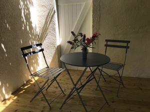 dos sillas y una mesa con un jarrón de flores en Les Fours à Chaux en Damiatte