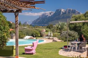 un cortile con piscina, tavolo e sedie di Hotel Ollastu a Costa Corallina