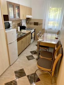 cocina con mesa y sillas y cocina con nevera en Anita Apartman en Hajdúszoboszló