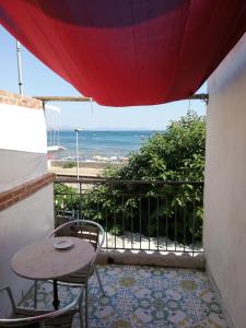 einen Tisch und Stühle auf einem Balkon mit Meerblick in der Unterkunft Hotel Sibilla Residence in Pozzuoli