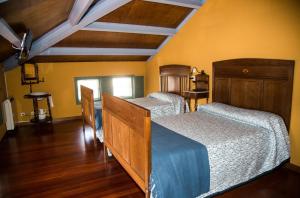 2 camas en una habitación con suelo de madera y paredes amarillas en Casa Don Din, en Cruces