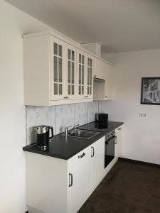 kuchnia z białymi szafkami i zlewem w obiekcie Apartment Ahrbergen w mieście Giesen