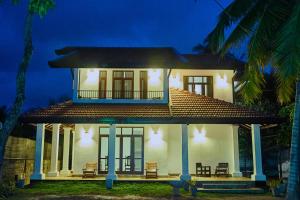 mały biały dom z werandą w nocy w obiekcie BIVORA Villa w Negombo