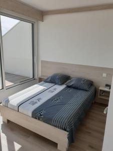 1 cama en un dormitorio con ventana grande en Le P'tit Benèze, en Royan