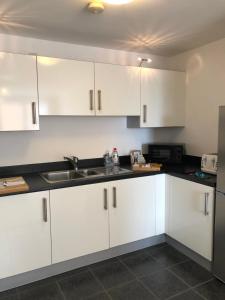 a kitchen with white cabinets and a sink at Hansen House 2 with Private Parking in Cardiff