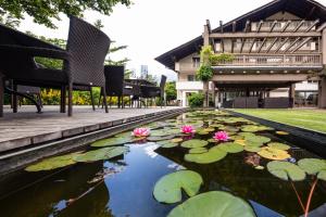 a pond with lilies and chairs and a building at Hotel Sand in Castelbello-ciardes