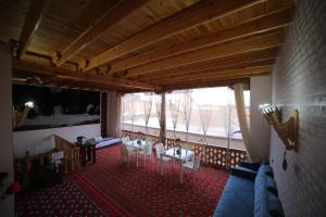 a room with tables and chairs and a large window at Rasulboy Guest House in Khiva