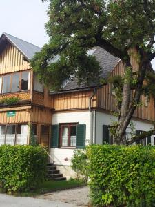 ein Haus mit einem Baum davor in der Unterkunft Appartements direkt am See in Grundlsee