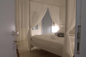 - une chambre blanche avec un lit à baldaquin et une fenêtre dans l'établissement Cocciu d'amuri, à San Vito Lo Capo