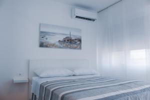 a white bedroom with a bed and a painting on the wall at City Center Studio 4 Two in Pula
