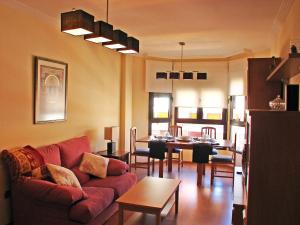 sala de estar con sofá rojo y comedor en Apartamentos Legazpi, en Albacete