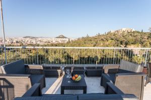 a balcony with blue chairs and a table with fruit on it at Acropolis Luxury Iris by GK Properties in Athens