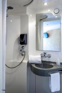 a bathroom with a sink and a mirror at Hôtel Moustache Lille - Seclin in Seclin