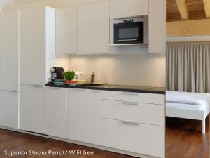 a kitchen with white cabinets and a microwave at Zermatt Appartements in Zermatt