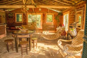 ein Wohnzimmer mit Bänken, einem Tisch und Stühlen in der Unterkunft Verdes Em Cantos Pousada in Carrancas