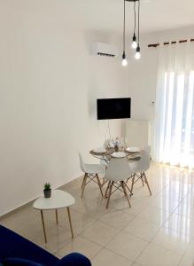 a dining room with a table and chairs and a tv at Minimal Apartment Center Kavala in Kavála