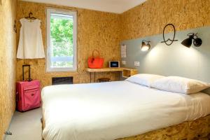 een slaapkamer met een wit bed en een roze koffer bij Hôtel Moustache Lille - Seclin in Seclin