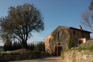 una vieja casa de piedra con un árbol delante en Romantic House en Greve in Chianti