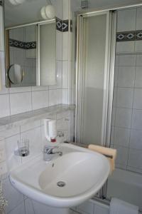 a white bathroom with a sink and a shower at Hotel-Restaurant Schwedi in Langenargen