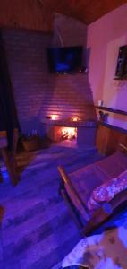 a living room with a brick fireplace with a tv at Chalés românticos com hidromassagem e lareira em área rural de visconde de Mauá Pousada Bela Helena in Visconde De Maua