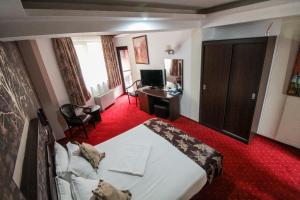 a hotel room with a large bed and a desk at Hotel Razvan in Bucharest