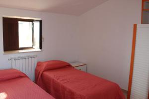 een slaapkamer met 2 bedden met rode lakens en een raam bij B&B A Due Passi in San Carlo