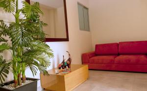 a living room with a red couch and a plant at Hotel Metropolitano Plaza in Valledupar
