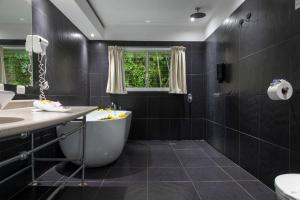 a bathroom with a sink, toilet and bathtub at El Faro Beach Hotel in Manuel Antonio