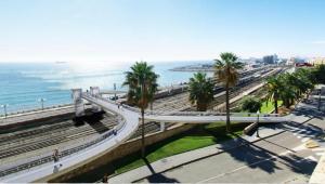 a bridge over a road with palm trees and the ocean at Apartamento supercéntrico "Tarraco Arena" con ascensor y parking incluído in Tarragona