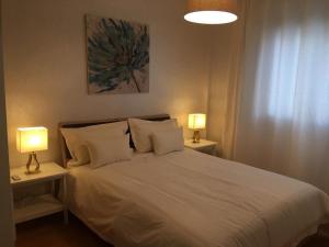 una camera con un letto bianco e 2 lampade di A 200m de la Plage, du Haut Standing au coeur du Parc a Mohammedia