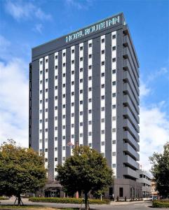 um grande edifício branco com um cartaz em Hotel Route-Inn Higashihiroshima Saijo Ekimae em Higashihiroshima