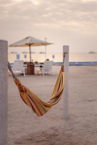 una hamaca en la playa con sillas y una sombrilla en Apartamento Frente a Islas Ballestas, en Paracas