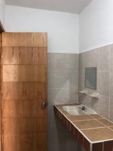 La salle de bains est pourvue d'un lavabo et d'une porte en bois. dans l'établissement Airport Sleepy Inn, à Cancún